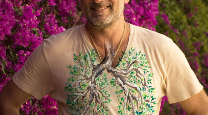 Leslie wearing a lung tree tee shirt in front of a beautiful magenta tree in Barcelona