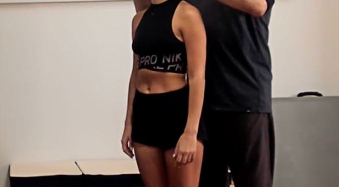 Leslie gently guiding a client, standing behind her with his fingers barely touching the sides of her head.